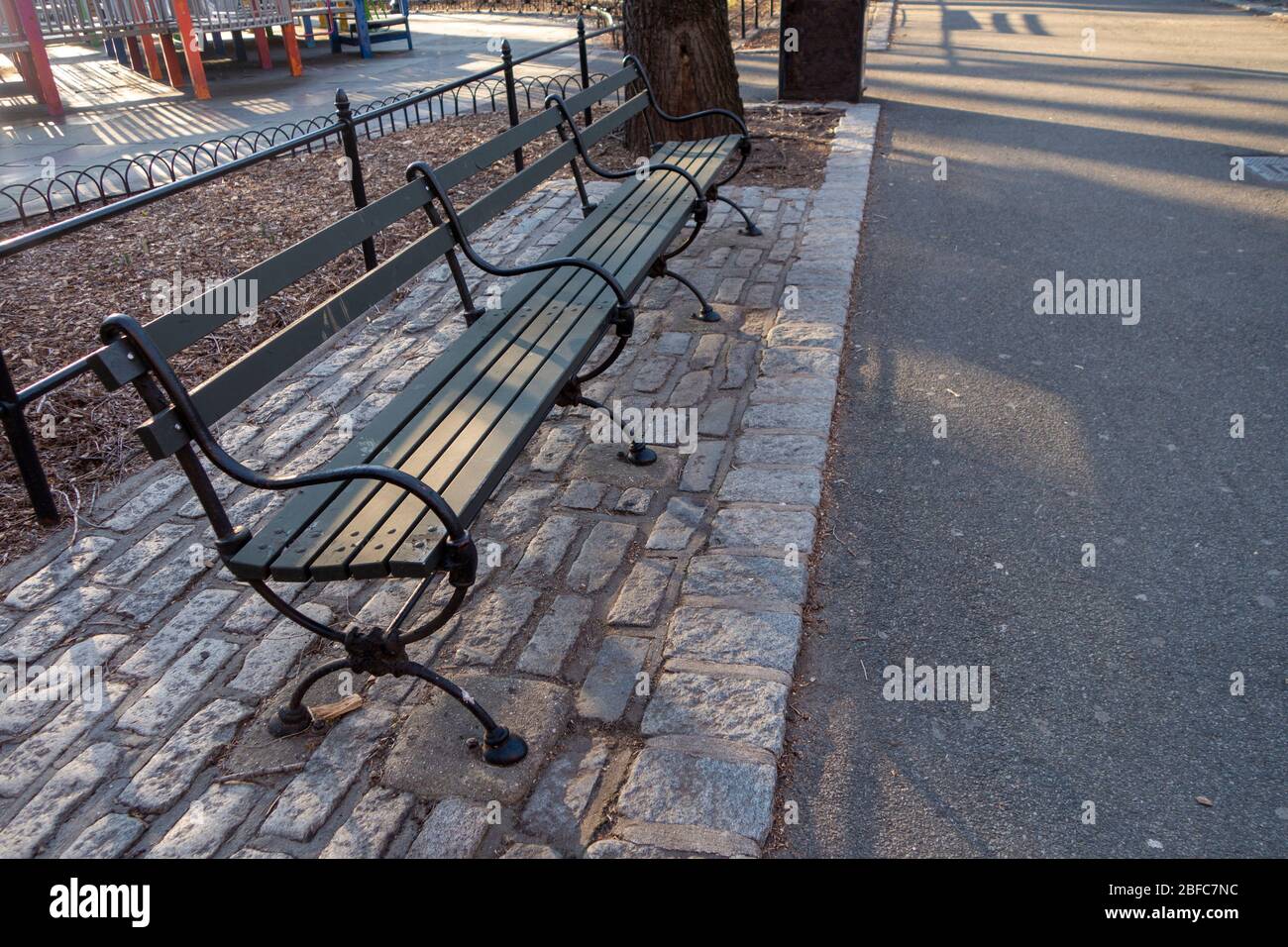 posti a sedere su panca in legno metallico classico, cementati nel marciapiede Foto Stock
