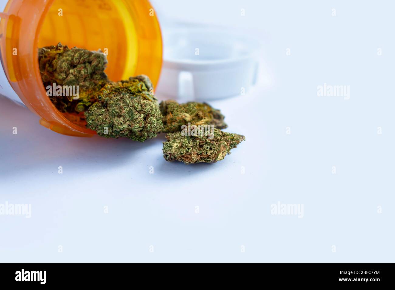 Marijuana medica C. marijuana medica che versa fuori da una bottiglia di prescrizione contro il bianco. Foto Stock