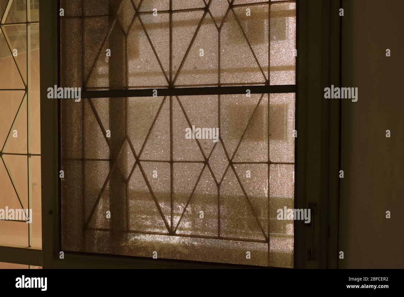 Primo piano trascurato schermo sporco porta, ferro battuto porta coperta con rete metallica, fotografia retroilluminata Foto Stock