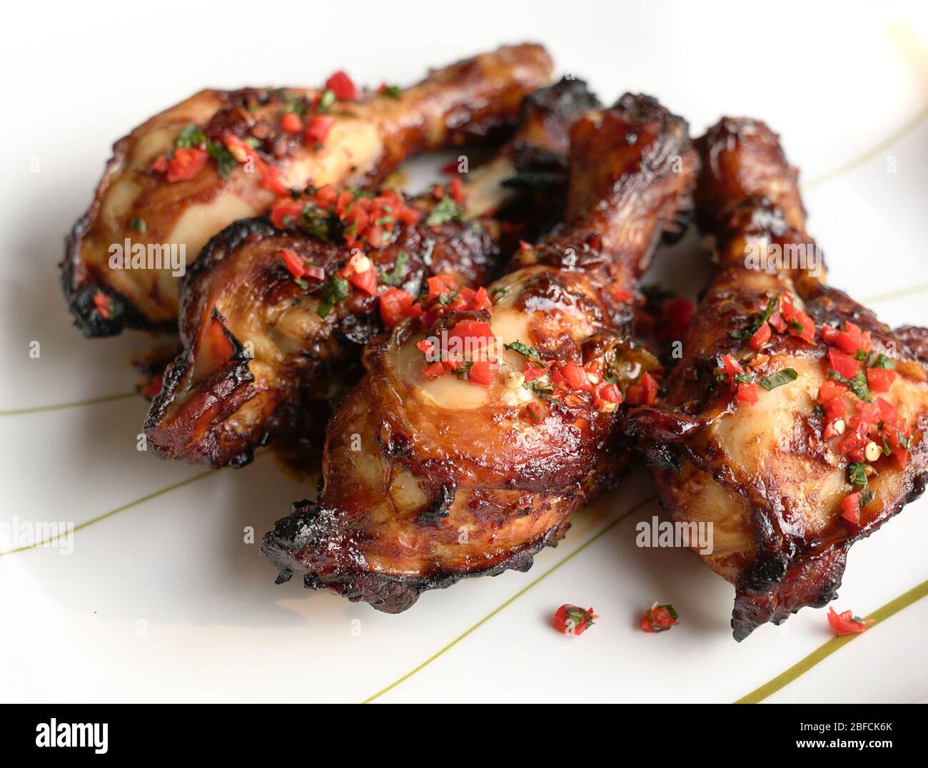 Bastoncini di pollo al forno. Servito su piatto bianco con foglie di peperoncino rosso tritato e menta. Foto Stock
