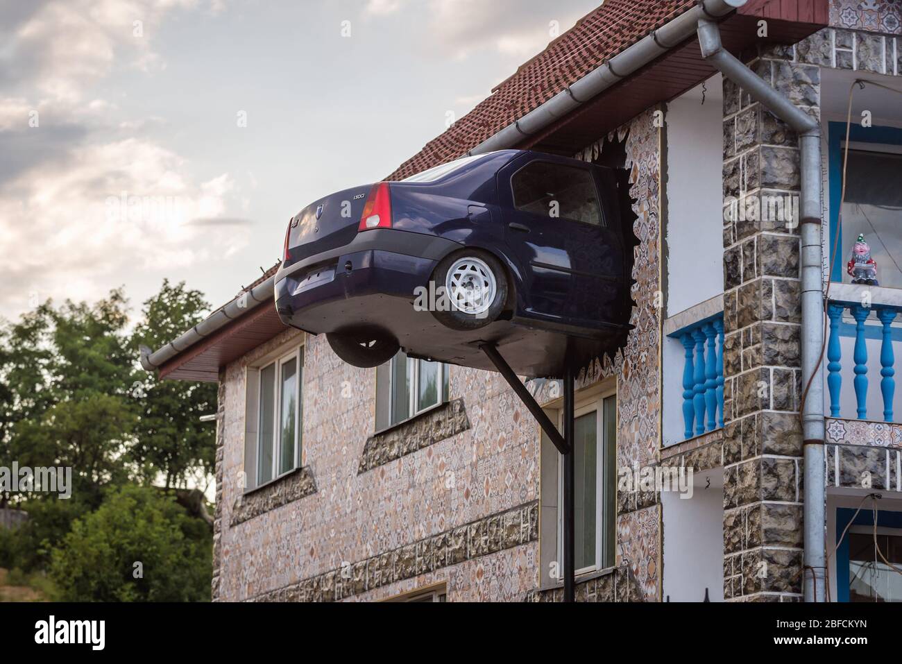 Bizzarro aggiunta casa - metà di Dacia Logan auto in un muro di Vasile Teascu casa in Teius città nella contea di Alba in Transilvania regione della Romania Foto Stock