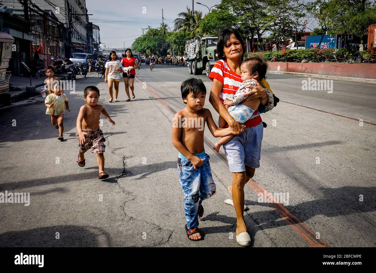 Distretto della capitale, Filippine. 18 Aprile 2020. (Nota per gli editori: Immagine acquisita dal dispositivo mobile). Donna vista portare un bambino come il fuoco spazzato attraverso "Happyland," una zona di baraccopoli a Manila Sabato, Barangay 105, zona 9, Distretto 1 e rapidamente diffusione, chiedendo al Bureau of Fire Protection di sollevare Task Force Alpha o di livello medio allarme. (Foto di Rick Mupas/Pacific Press) Credit: Pacific Press Agency/Alamy Live News Foto Stock