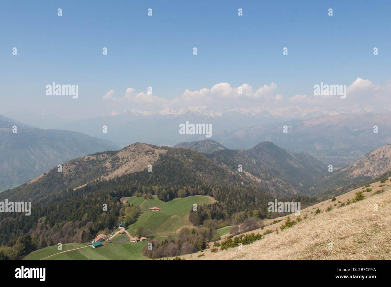 La vista del contryside rurale in montagna. Campi agricoli su colline con montagne sullo sfondo. Foto Stock