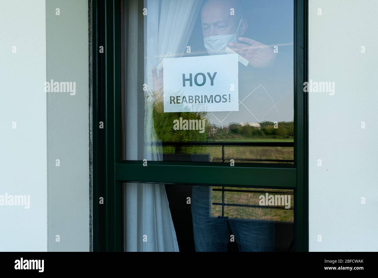 un uomo attacca oggi che apriamo in lingua spagnola sulla porta del negozio. Foto Stock