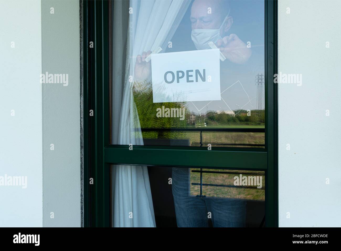 Un uomo attacca il cartello Open sulla porta del negozio Foto Stock