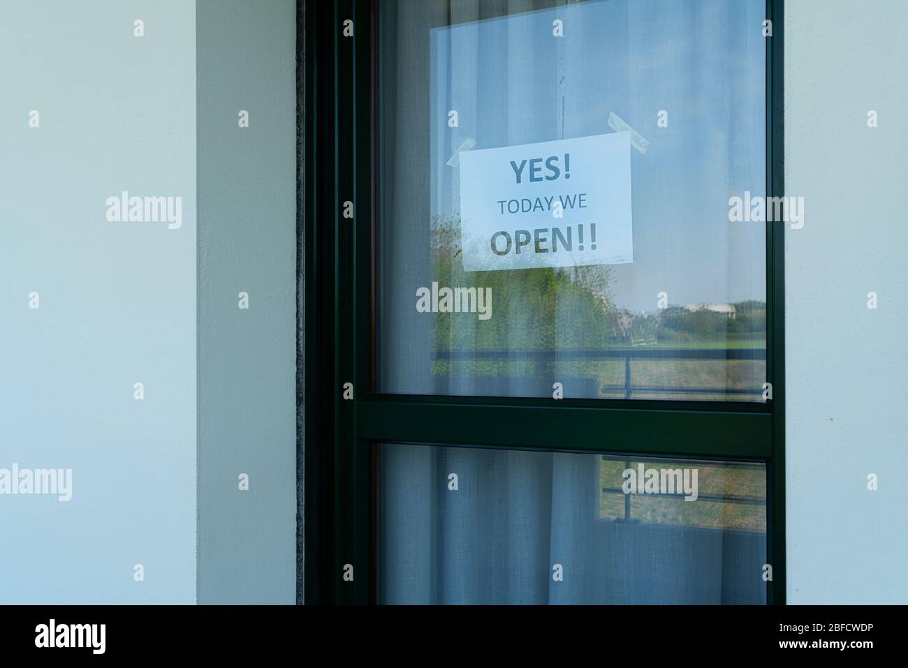 Un uomo attacca il Sì, oggi apriamo il segno sulla porta del negozio. Foto Stock