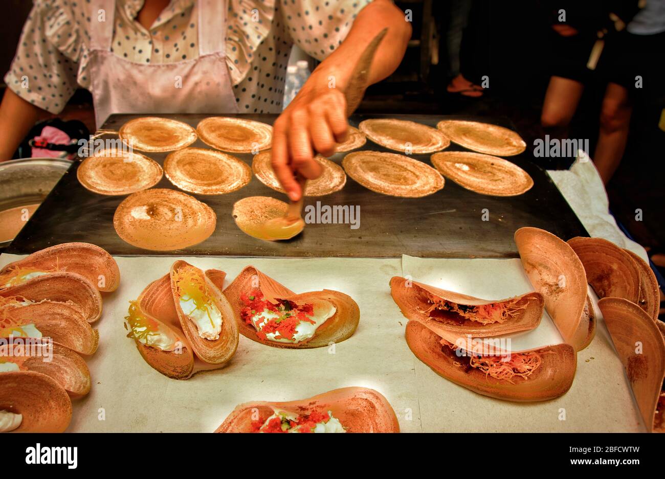 Vendita di cibo di strada che cucina e vende spuntini tradizionali chiamati khanom bueang o crepe croccante thailandese, mostrando la cultura locale e la cucina della Thailandia Foto Stock