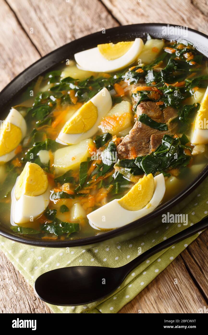 Zuppa di spinaci con carne, verdure e uova in primo piano in una ciotola sul tavolo. Verticale Foto Stock