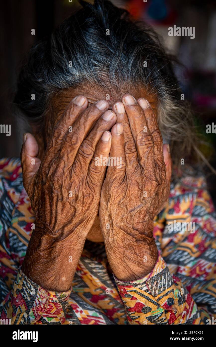 Nonna sconosciuta che tocca il suo viso con le mani grinze. Foto Stock