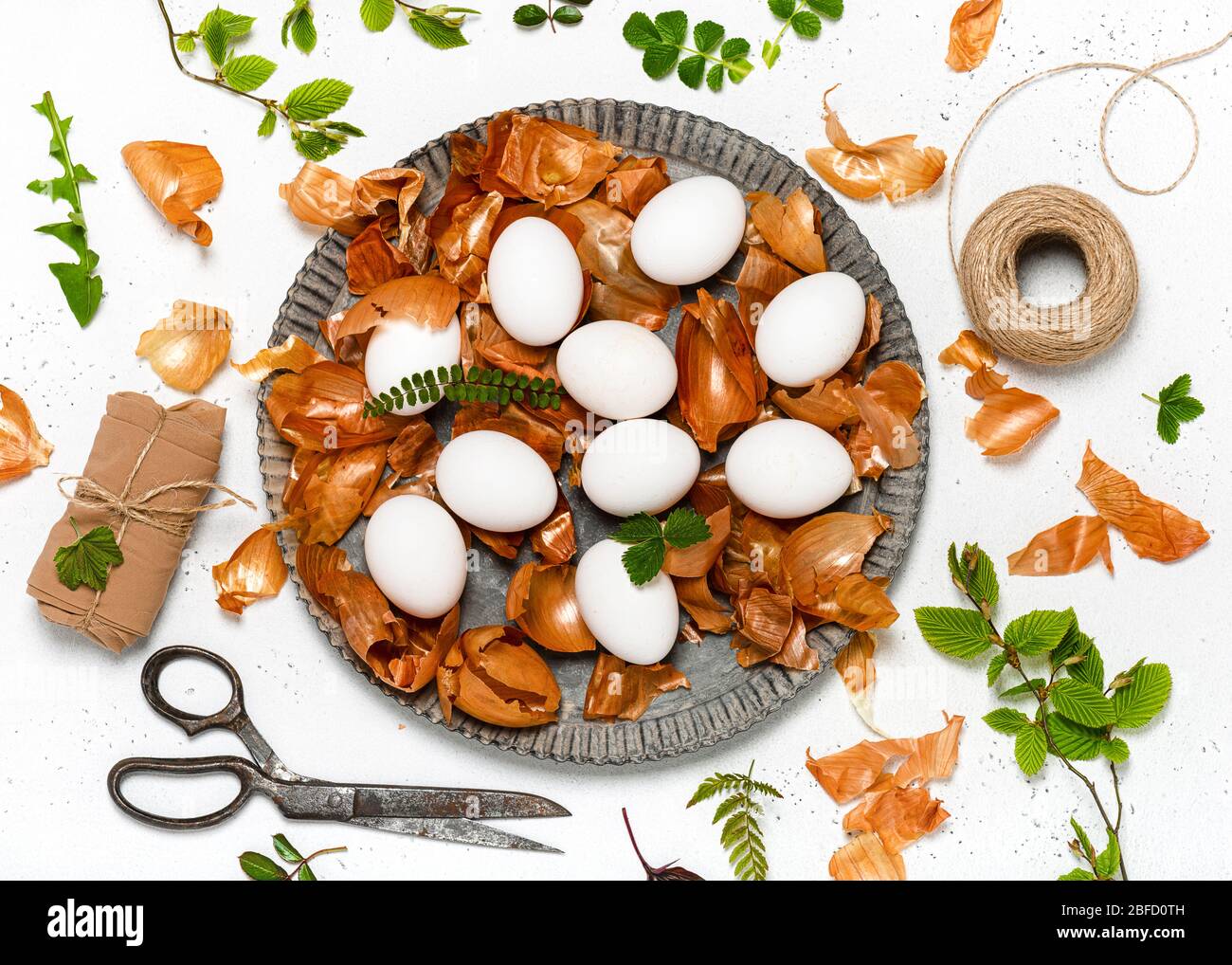 Preparazione delle uova di Pasqua per la tintura con bucce di cipolla e disegno di foglie fresche. Colorazione ecologica naturale con colorazione alimentare. Vista dall'alto. Foto Stock