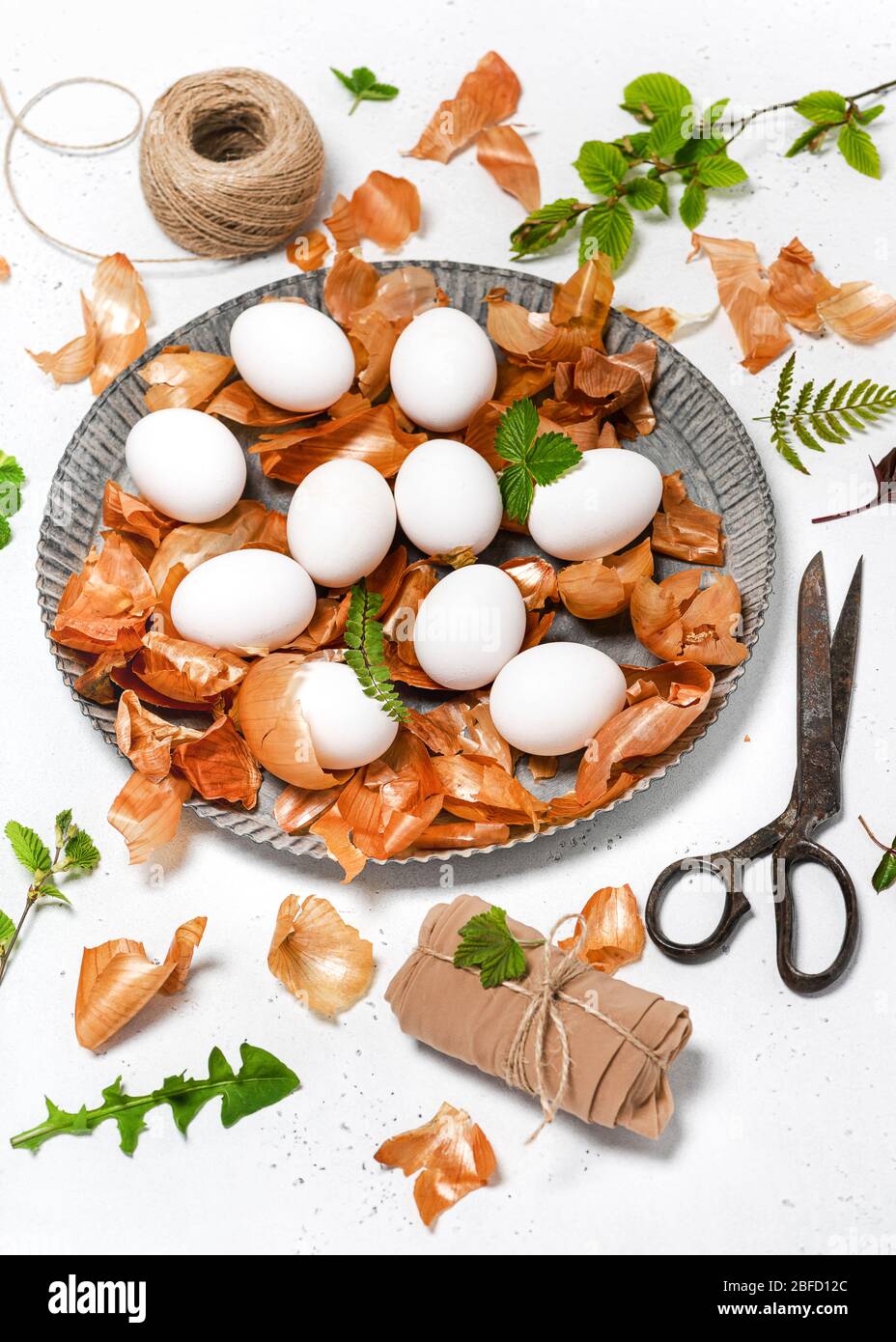Preparazione delle uova di Pasqua per la tintura con bucce di cipolla e disegno di foglie fresche. Colorazione ecologica naturale con colorazione alimentare. Messa a fuoco selettiva. Foto Stock