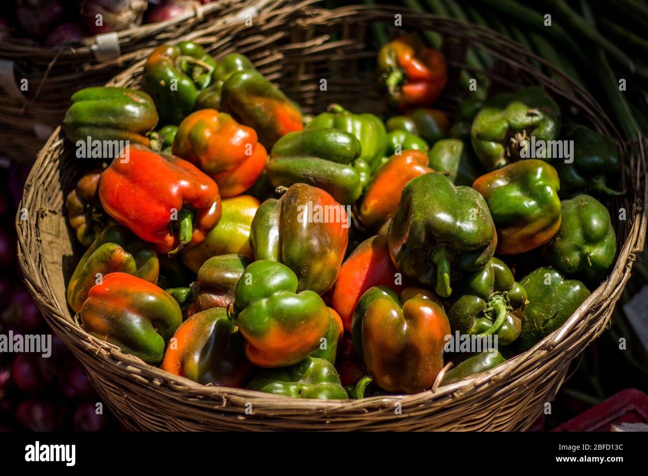 Vendita capsicum filo cesto di verdure ciotola sul mercato di strada. Capsicum rosso e verde misto in vendita su cesto di verdure. Foto Stock