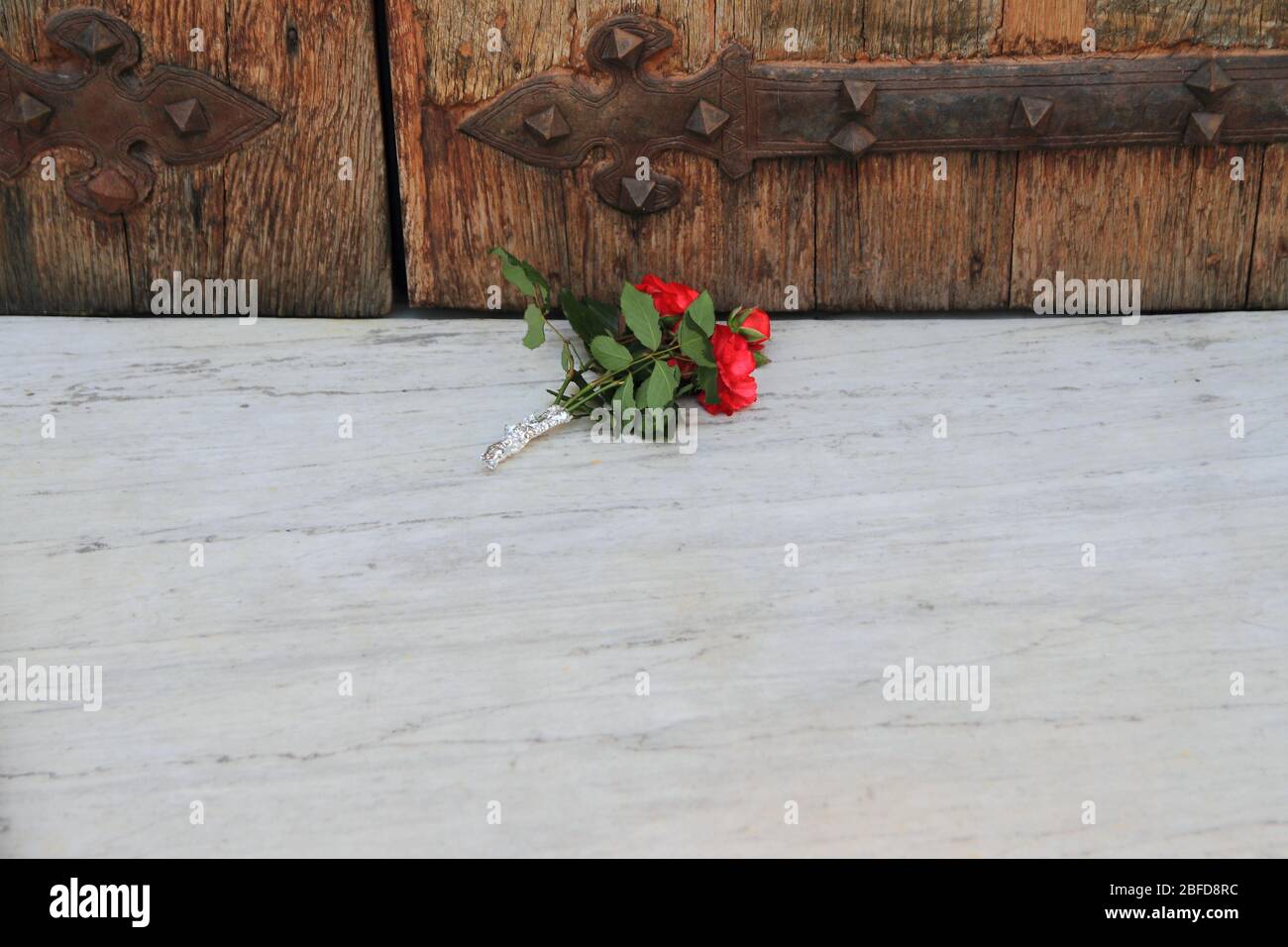 Un mazzo di fiori messo a terra davanti alla porta chiusa in legno del Santuario di nostra Signora del Carmelo, durante la chiusura Foto Stock
