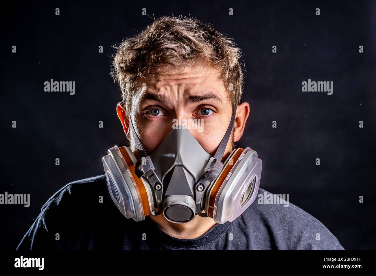 Uomo in maschera respiratore con un grado maggiore di protezione contro fattori ambientali nocivi. Maschera facciale parziale. Isolare il concetto di paura del virus. Foto Stock