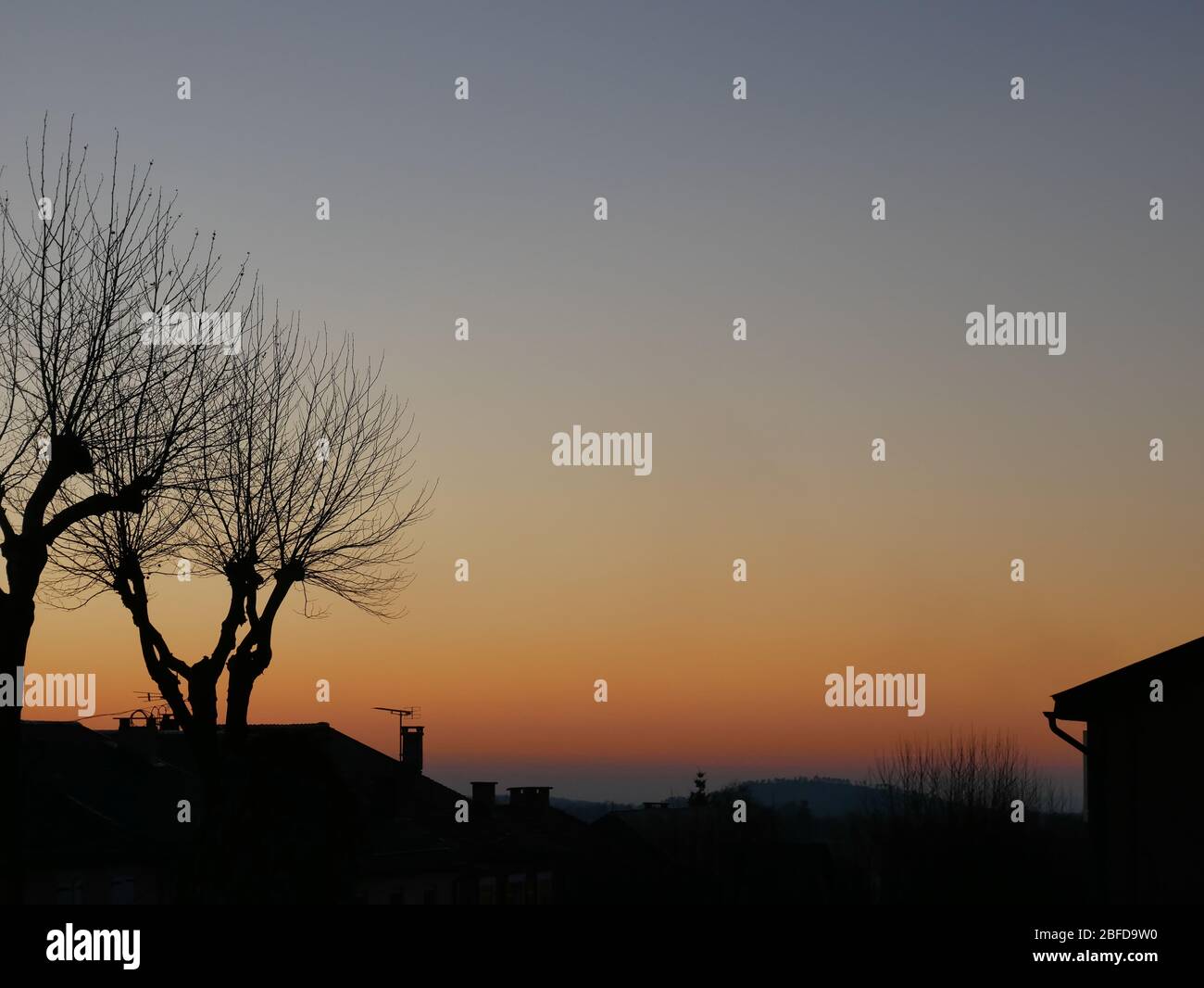 Silhouette di alberi e tetti di casa al tramonto in un villaggio nel sud della Francia Foto Stock