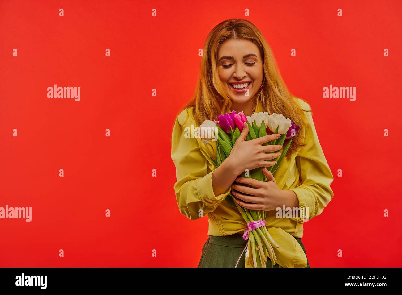 Belle donne con il sorriso in una blusa e una gonna con un bouquet di fiori in mano. Foto Stock