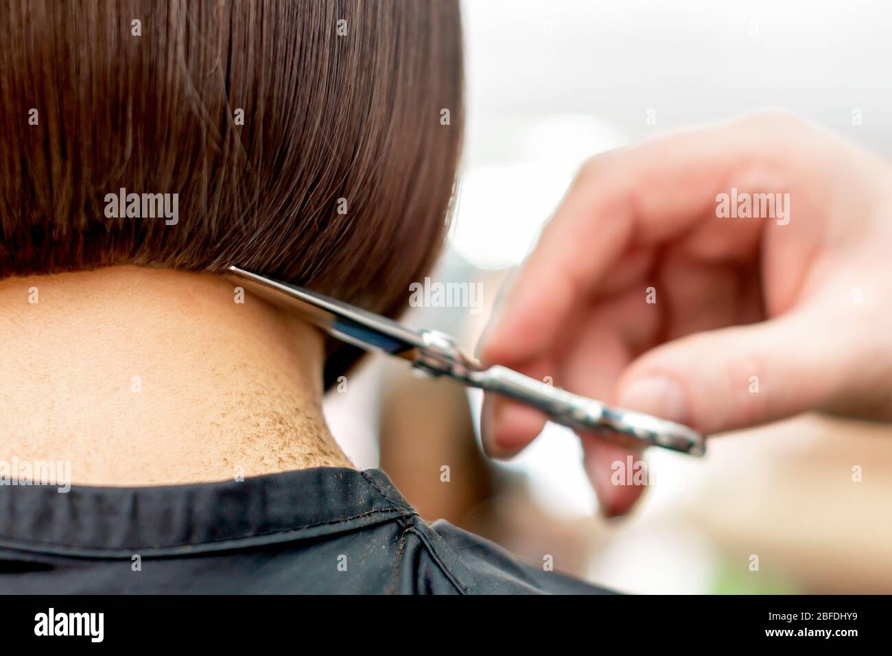 La mano del parrucchiere sta tagliando le punte dei capelli della donna hairstyle corto, vista posteriore con spazio di copia. Foto Stock