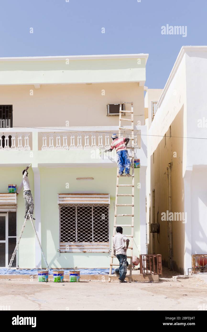 Tre uomini locali che dipingere una casa a 2 piani a Nouakchott, Mauritania. Foto Stock