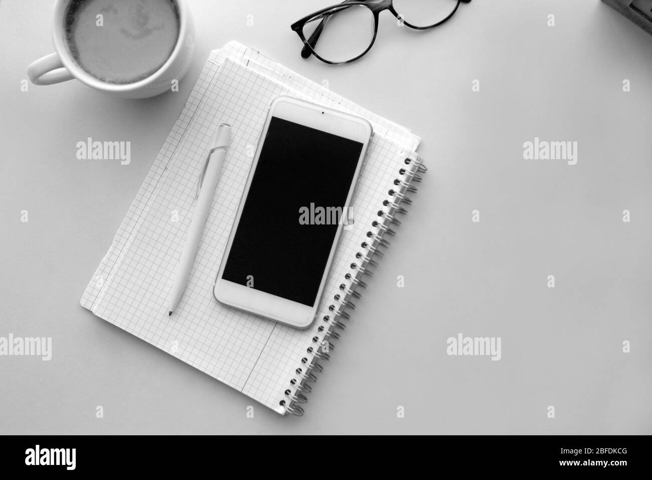 Telefono cellulare e carta per appunti. Interni in stile retrò - accogliente luogo di lavoro a casa interni eleganti in caldi colori pastello, tavolo e tazza da caffè bianco Foto Stock