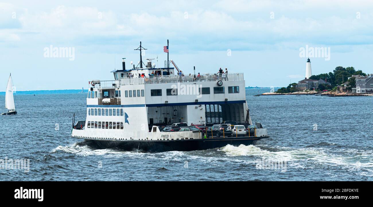 New London, Connecticut, USA - 27 luglio 2017: Traghetto che trasporta le automobili che lasciano New London Connecticut con il faro e barca a vela nel backgroun Foto Stock