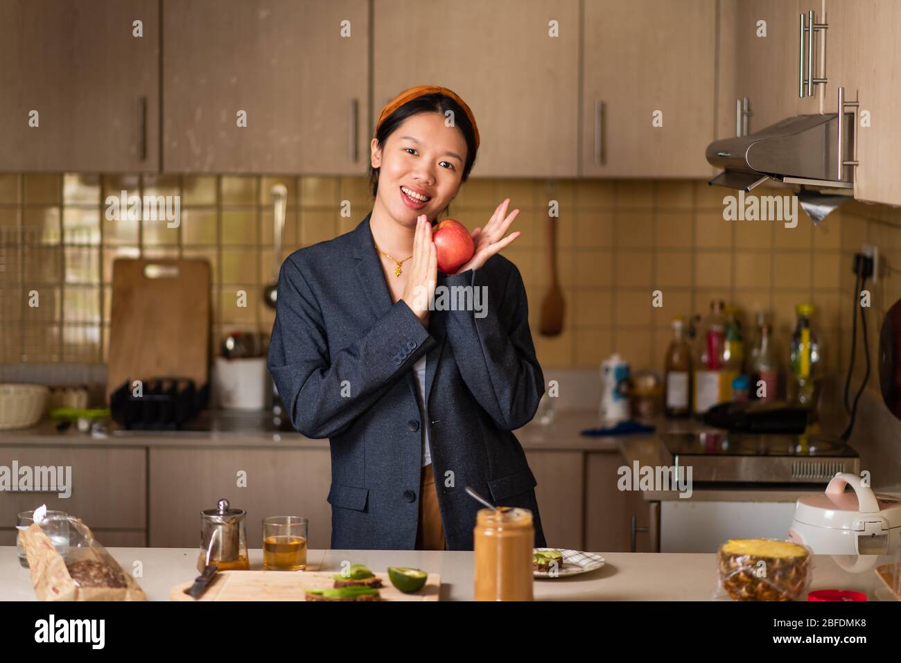 Allegra donna asiatica ingannare tenendo una mela in cucina Foto Stock
