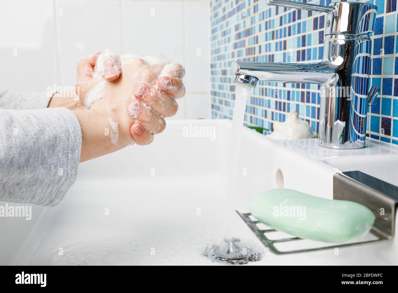 Il bambino lava diligentemente le mani con sapone antibatterico e acqua eseguendo le misure protettive di base contro la diffusione di deseas COVID-19 di coronavirus Foto Stock