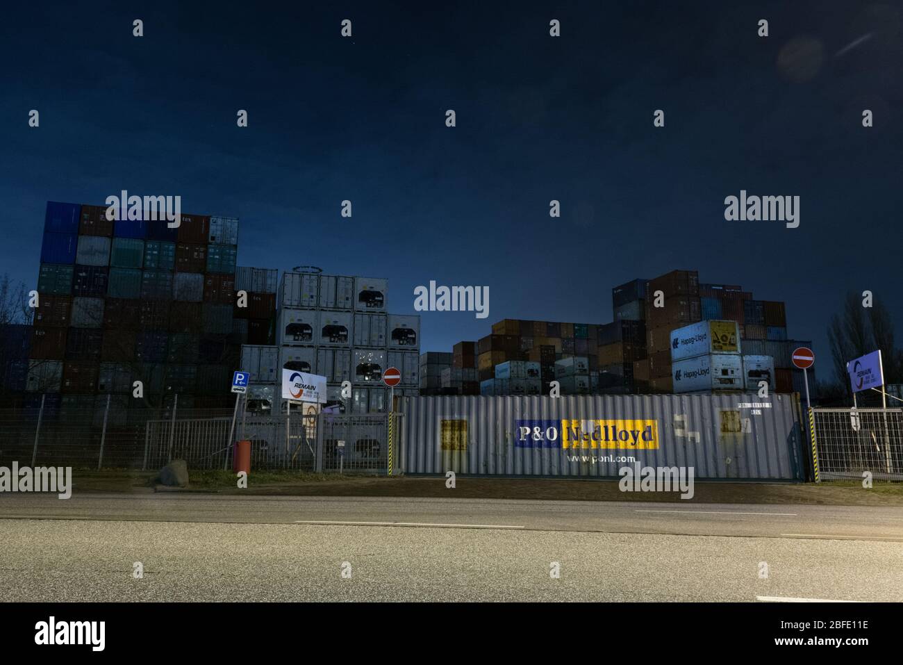 Area container del porto di Amburgo di notte - foto a lunga esposizione con le auto che passano e i loro fasci di luce Foto Stock