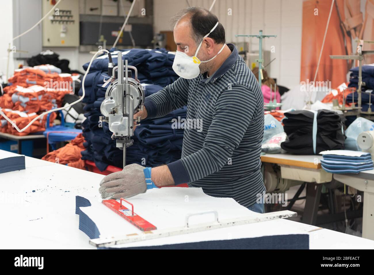 Un operaio di fabbrica taglia l'abbigliamento medico per il NHS (Servizio sanitario Nazionale) alla fabbrica di Fashion-Enter Ltd. Foto Stock