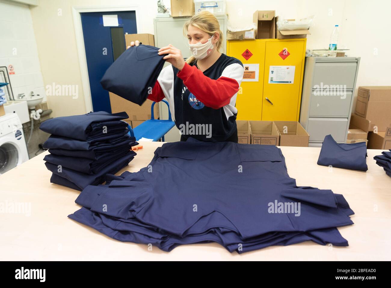 Un operaio di fabbrica piega e scatole l'abbigliamento medico per il NHS (Servizio sanitario Nazionale) alla fabbrica di Fashion-Enter Ltd. Foto Stock