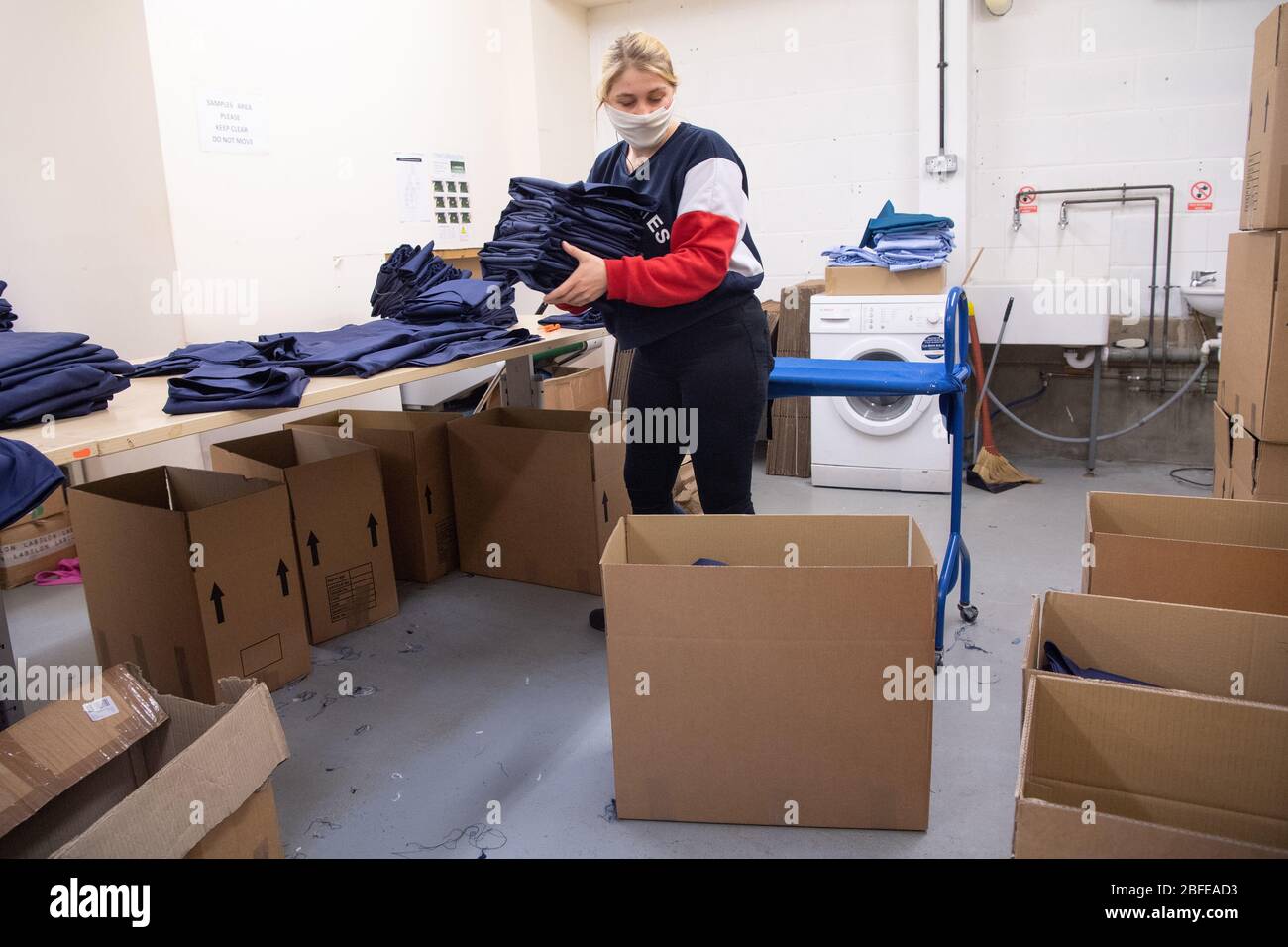 Un operaio di fabbrica inscatolano l'abbigliamento medico per il NHS (Servizio sanitario Nazionale) alla fabbrica della Fashion-Enter Ltd. Foto Stock