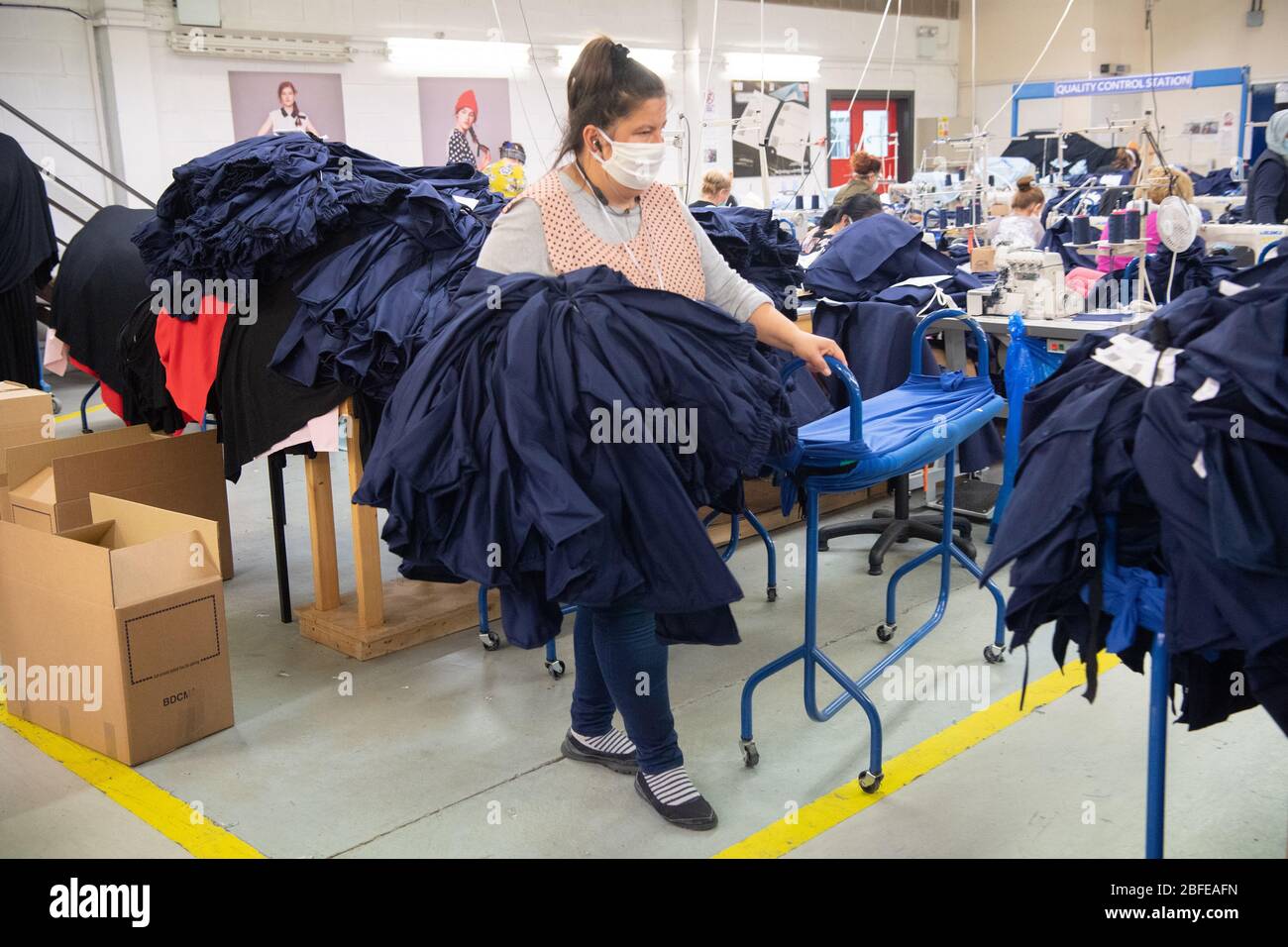 Un lavoratore della fabbrica trasporta l'abbigliamento medico per il NHS (Servizio sanitario Nazionale) alla fabbrica della Fashion-Enter Ltd. Foto Stock