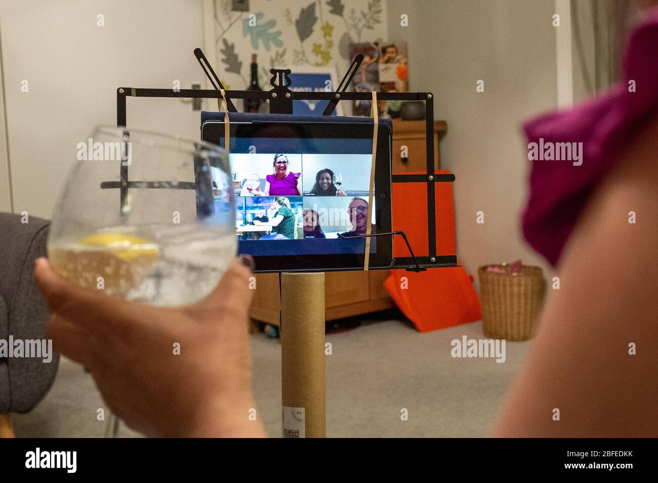 Donna di mezza età siede nella sua casa bere alcol, parlando con gli amici tramite la videotelecomunicazione Zoom durante la pandemia di Coronavirus in Regno Unito Foto Stock