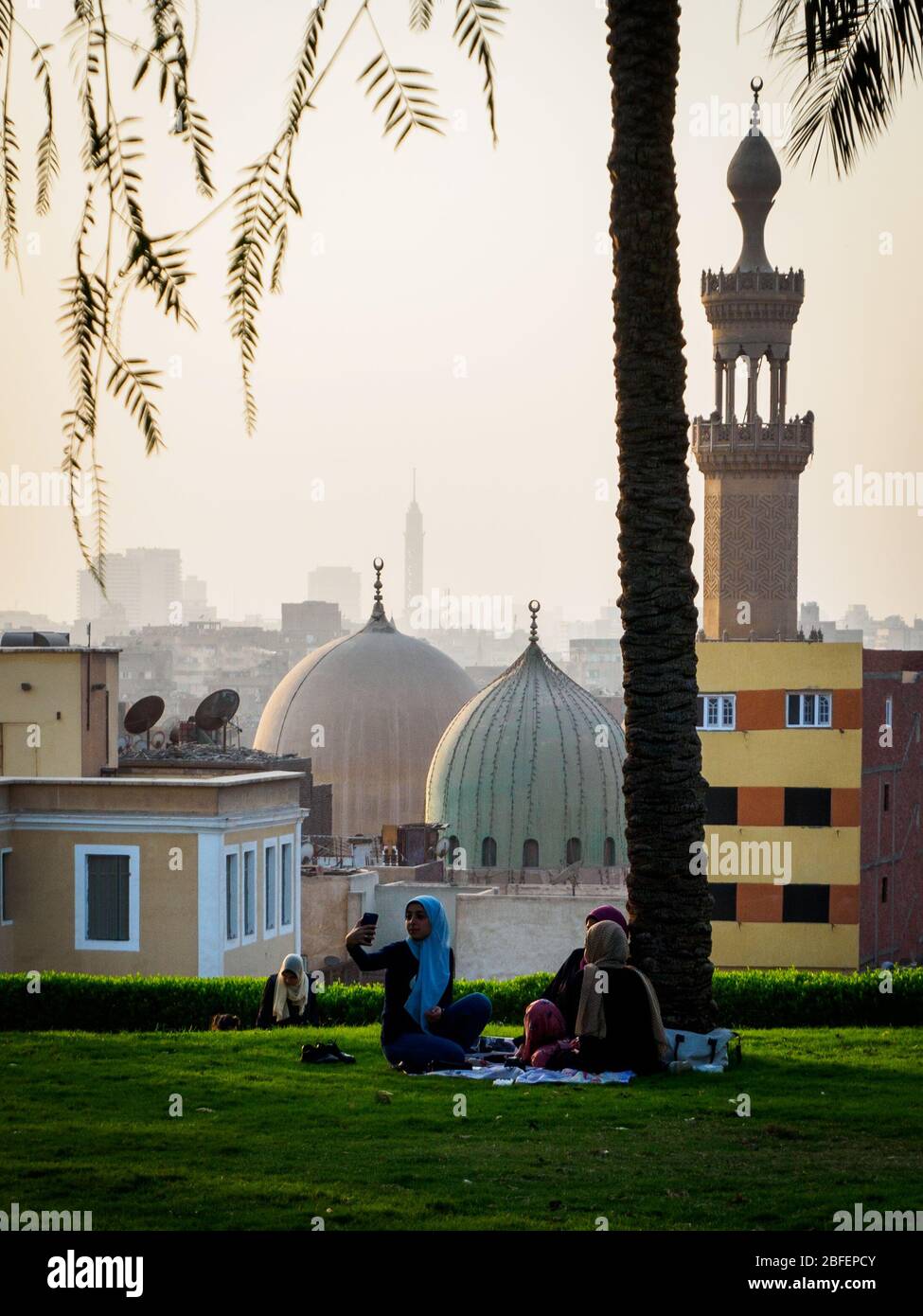 Al Azhar Park, Cairo, Egitto, 2019 ottobre, tre ragazze sedute su una coperta nel parco con lo skyline del Cairo sullo sfondo Foto Stock