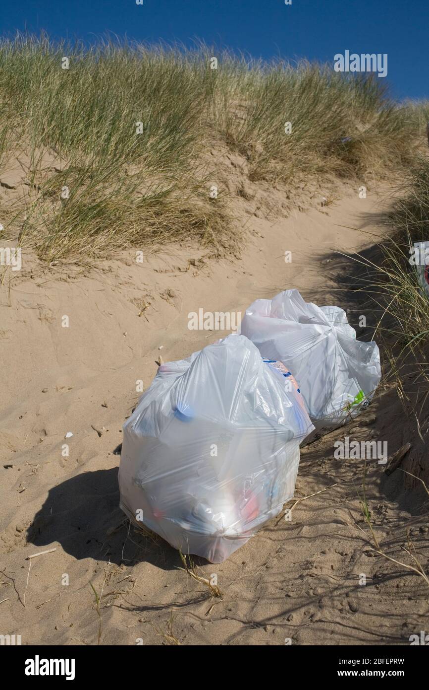 Sentiero sabbioso che conduce alle dune di Merthyr Mawr da Newton Beach con borse di spazzatura in attesa di raccolta Foto Stock