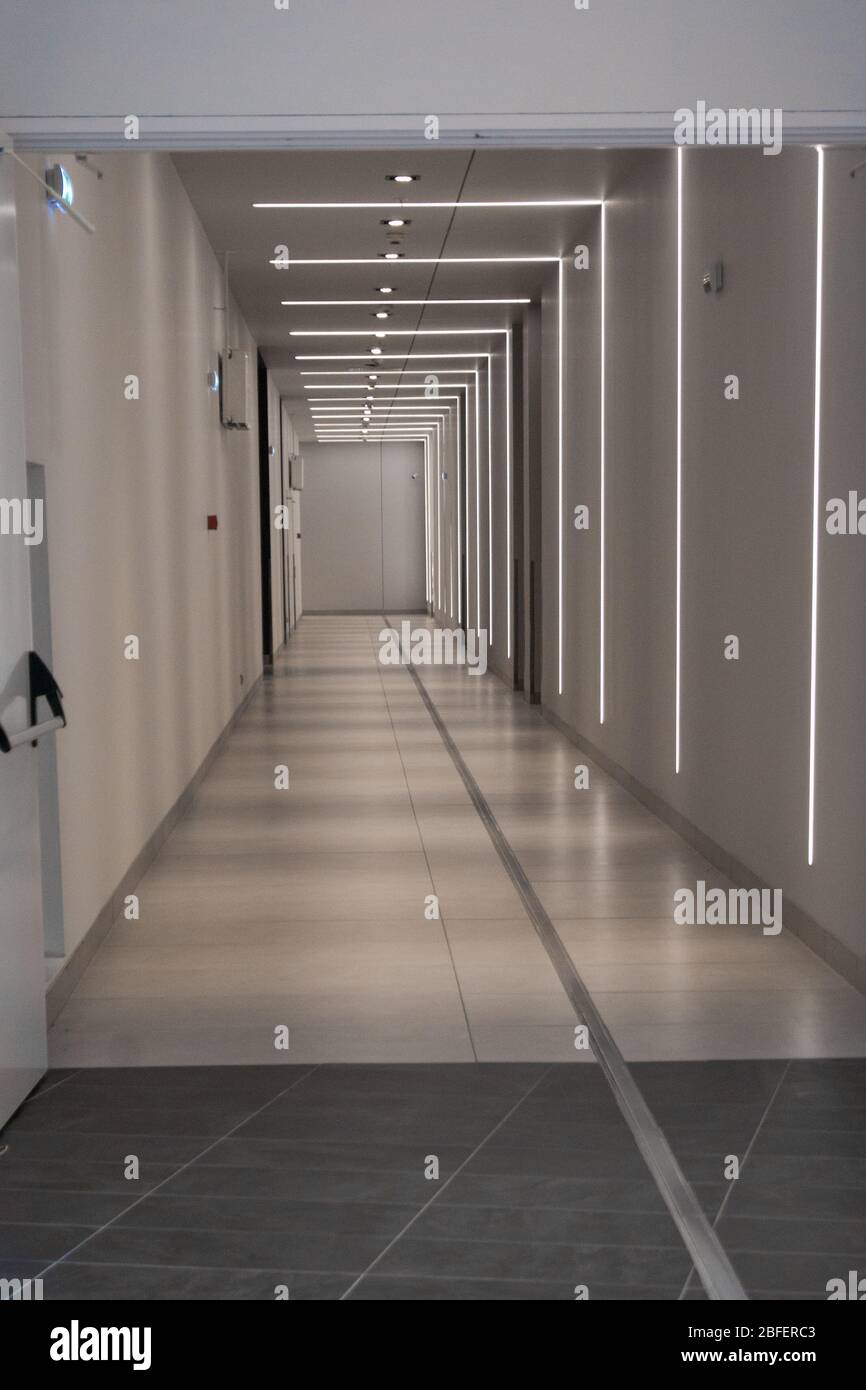 Un lungo e lungo passaggio vuoto in metropolitana con un'interessante retroilluminazione geometrica che forma un ritmo visivo. Tunnel, luce, infinito Foto Stock