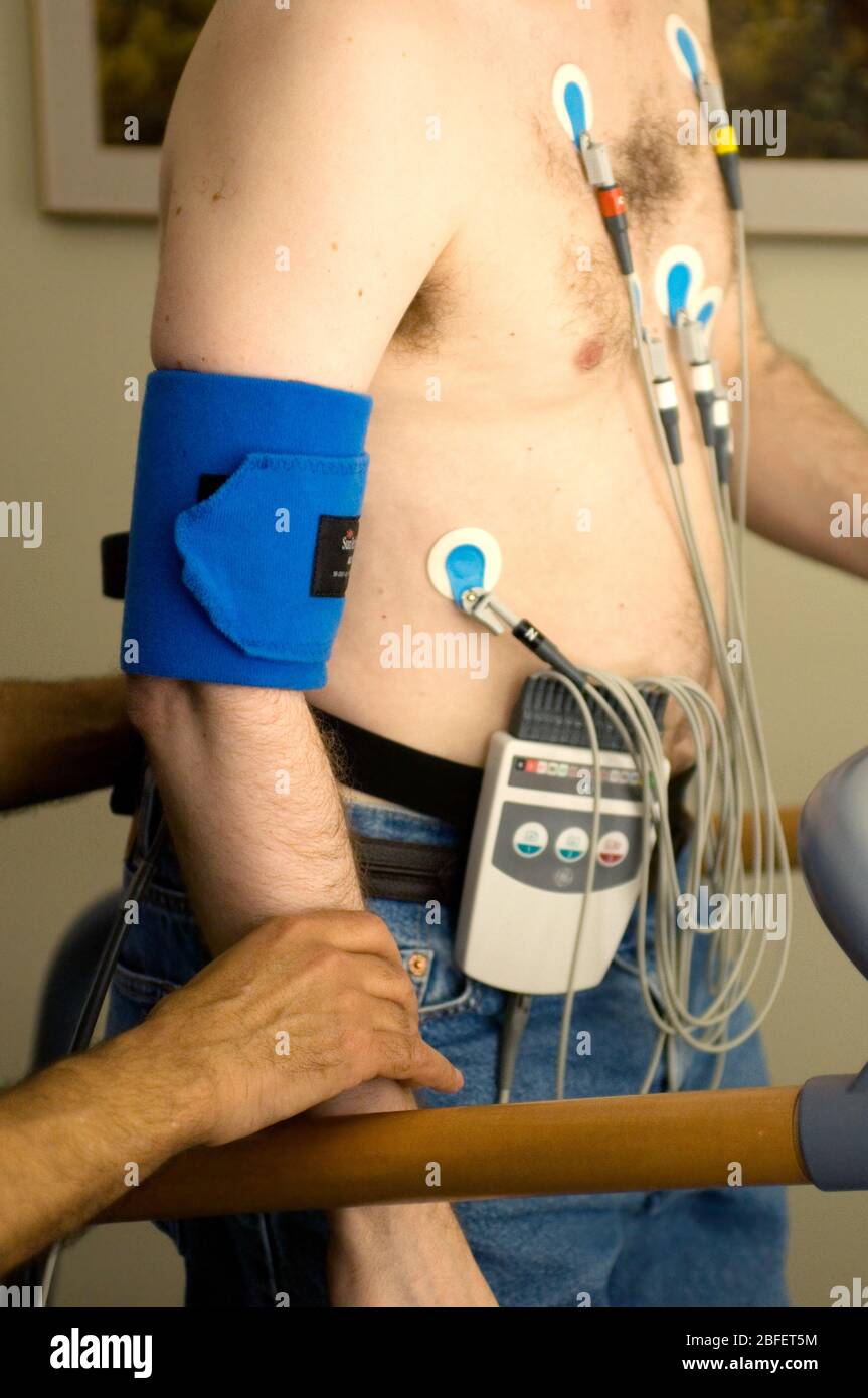 Un uomo che subisce un test di sforzo di esercizio camminare su un tapis roulant mentre collegato fino ad un'apparecchiatura che controlla la sua frequenza cardiaca, respirazione, pressione sanguigna, Foto Stock