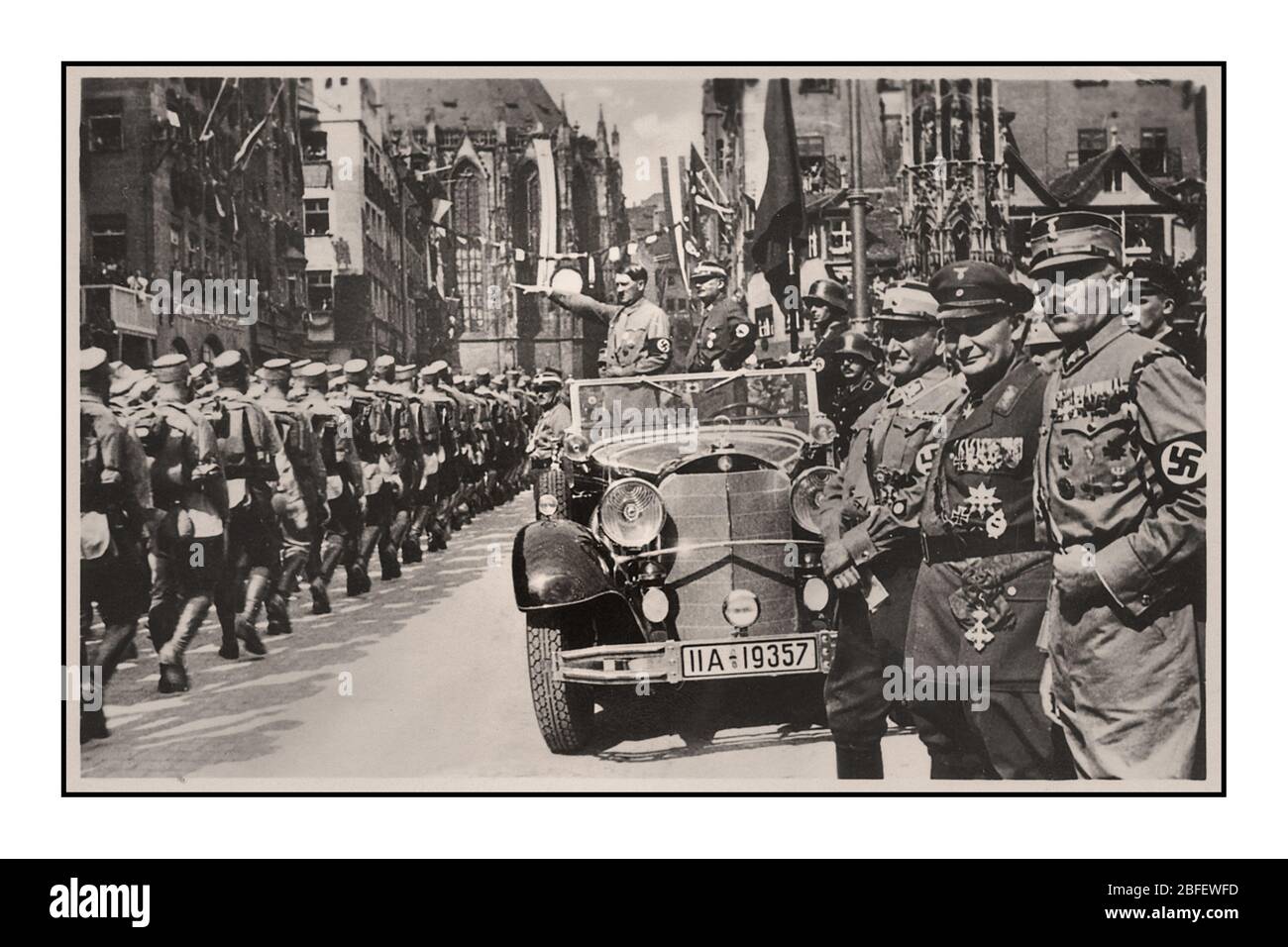Vintage Norimberga Rally 1935, Germania - SA Sturmabteilung truppe politiche del partito nazista, marcia oltre Adolf Hitler durante una parata in città. Adolf Hitler degli anni '30 indossa la banda militare della Swastika nella parata militare, in piedi in Mercedes con Heil Hitler salutare il passaggio in marcia Sturmabteilung truppe Hermann Goring in primo piano Norimberga Germania Foto Stock