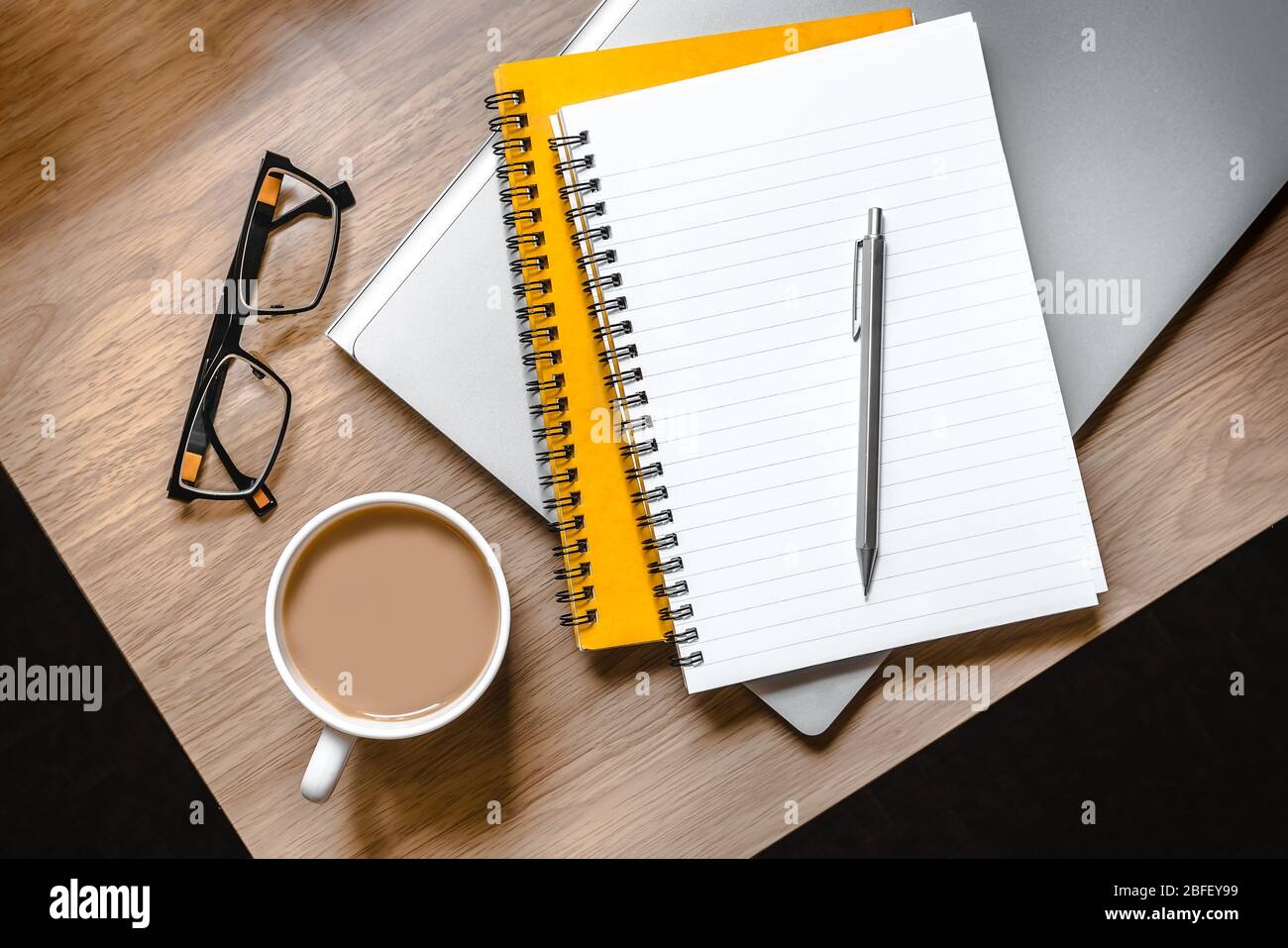 WFH - Foto di scrivania con laptop, blocco note, bicchieri e tazza di tè Foto Stock