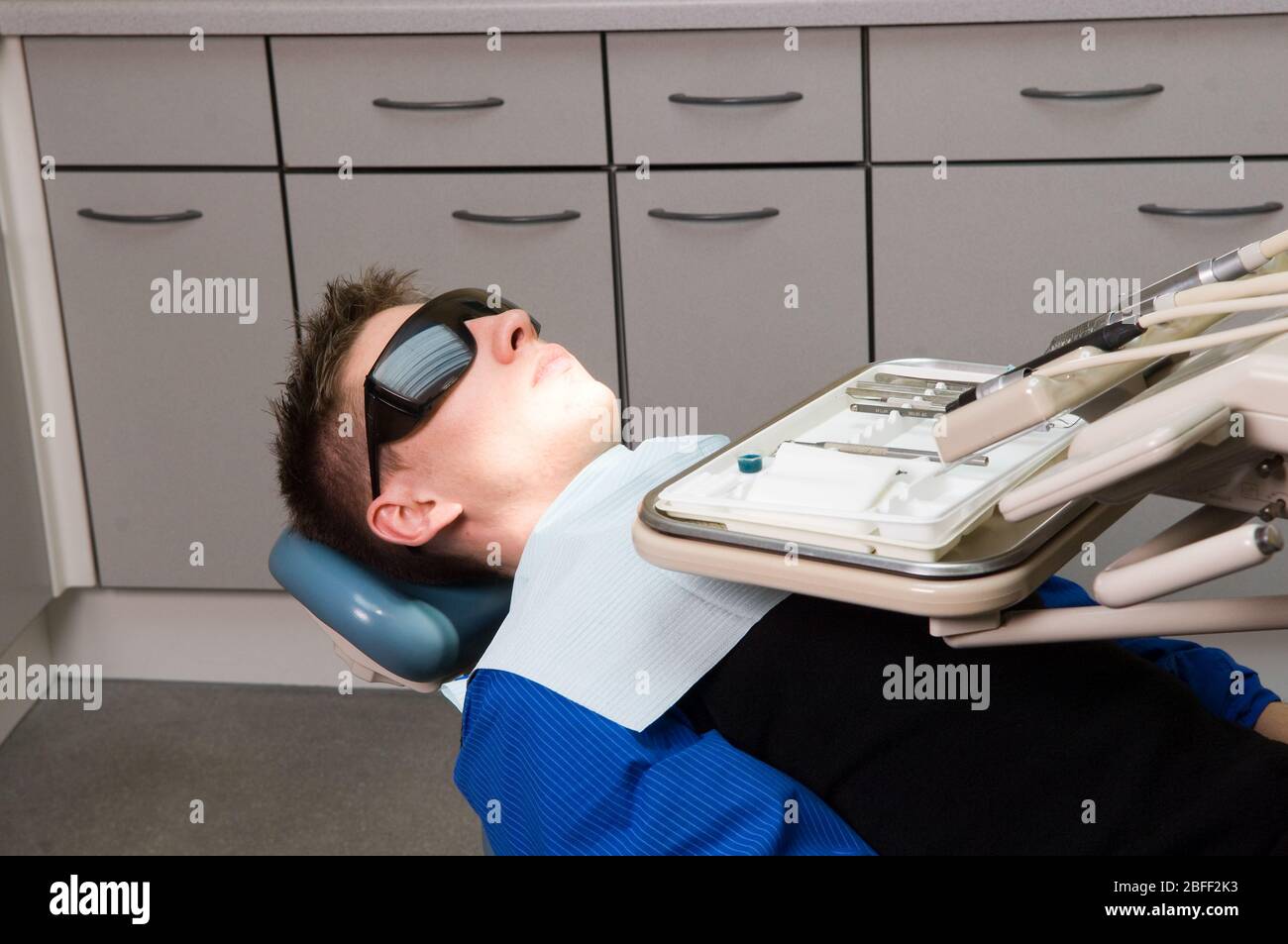 Giovane paziente di sesso maschile sulla sedia del dentista davanti a un  vassoio di strumenti dentali. (Modello rilasciato)(Medicimage Foto stock -  Alamy