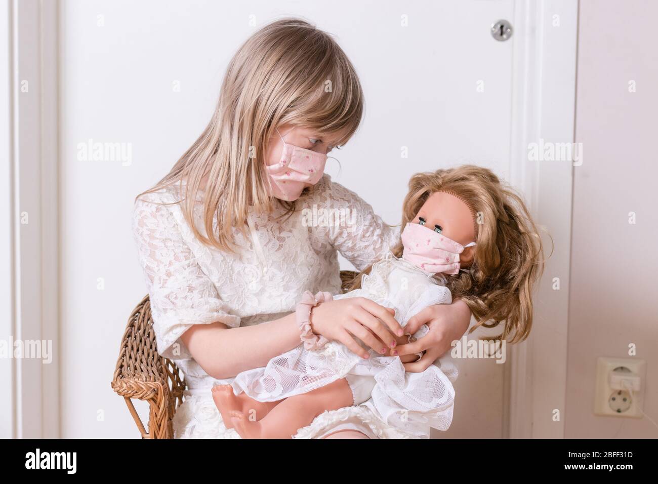 ragazza con covid 19 maschera di protezione fatta in casa con la sua bambola Foto Stock