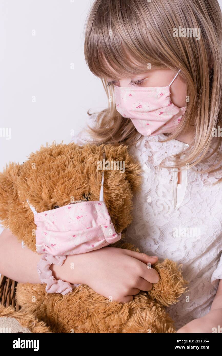 ragazza con covid 19 maschera di protezione fatta in casa con il suo orsetto Foto Stock