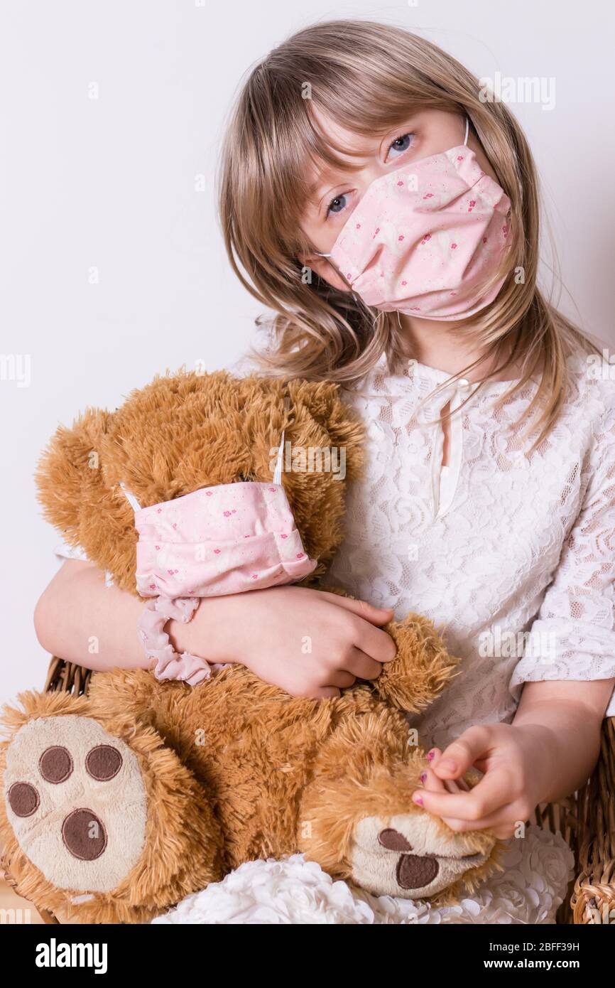 ragazza con covid 19 maschera di protezione fatta in casa con il suo orsetto Foto Stock