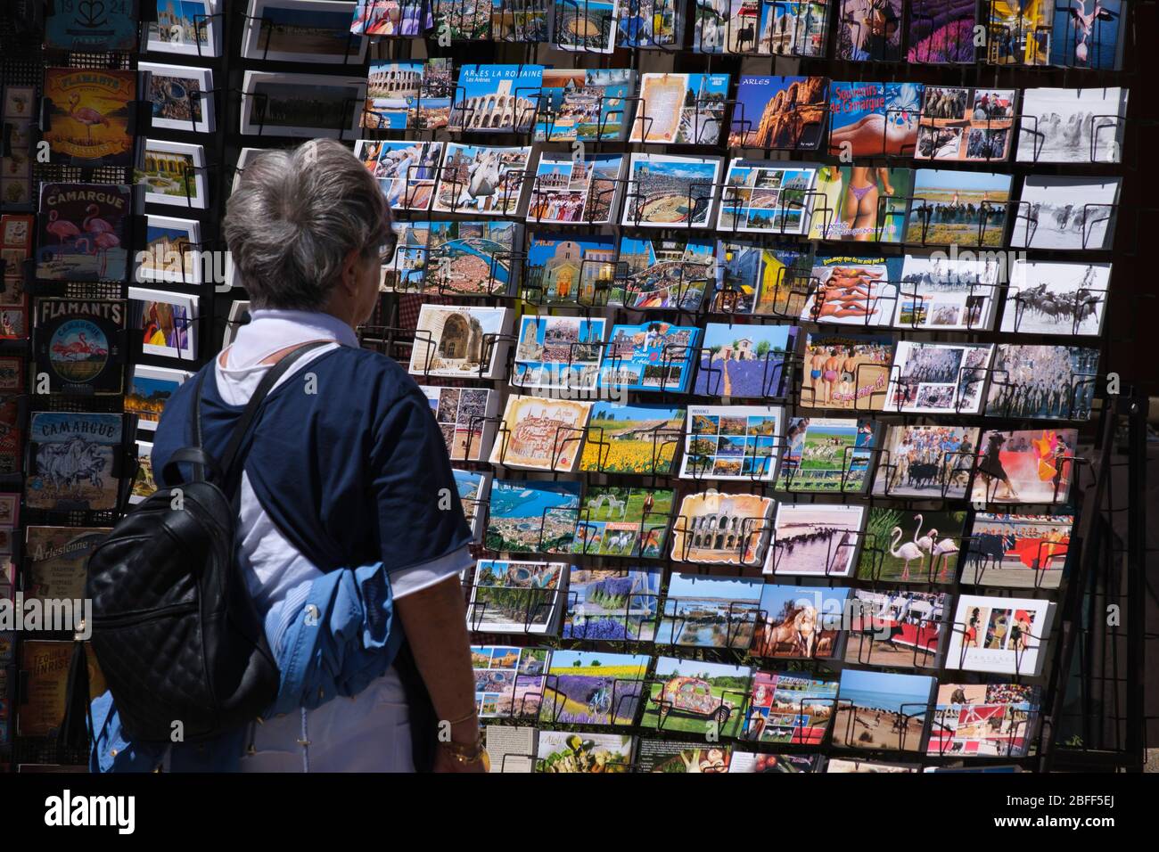 Donna che guarda le cartoline in mostra in un negozio di souvenir ad Arles, Francia, Europa Foto Stock