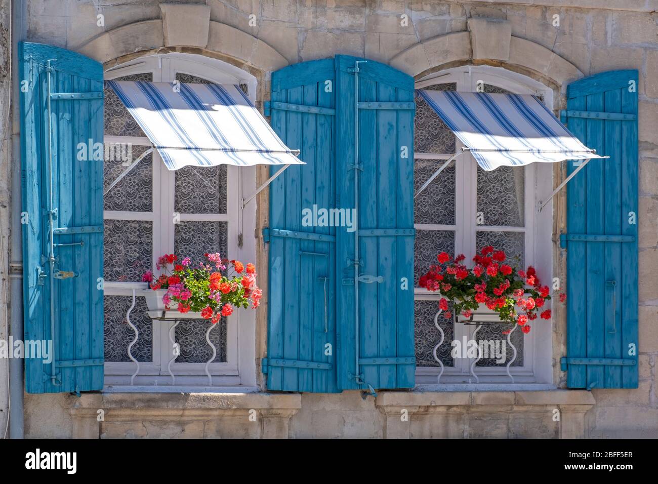 Due finestre chiuse con persiane blu e scatole di fiori ad Arles, Provenza, Francia meridionale, Europa Foto Stock