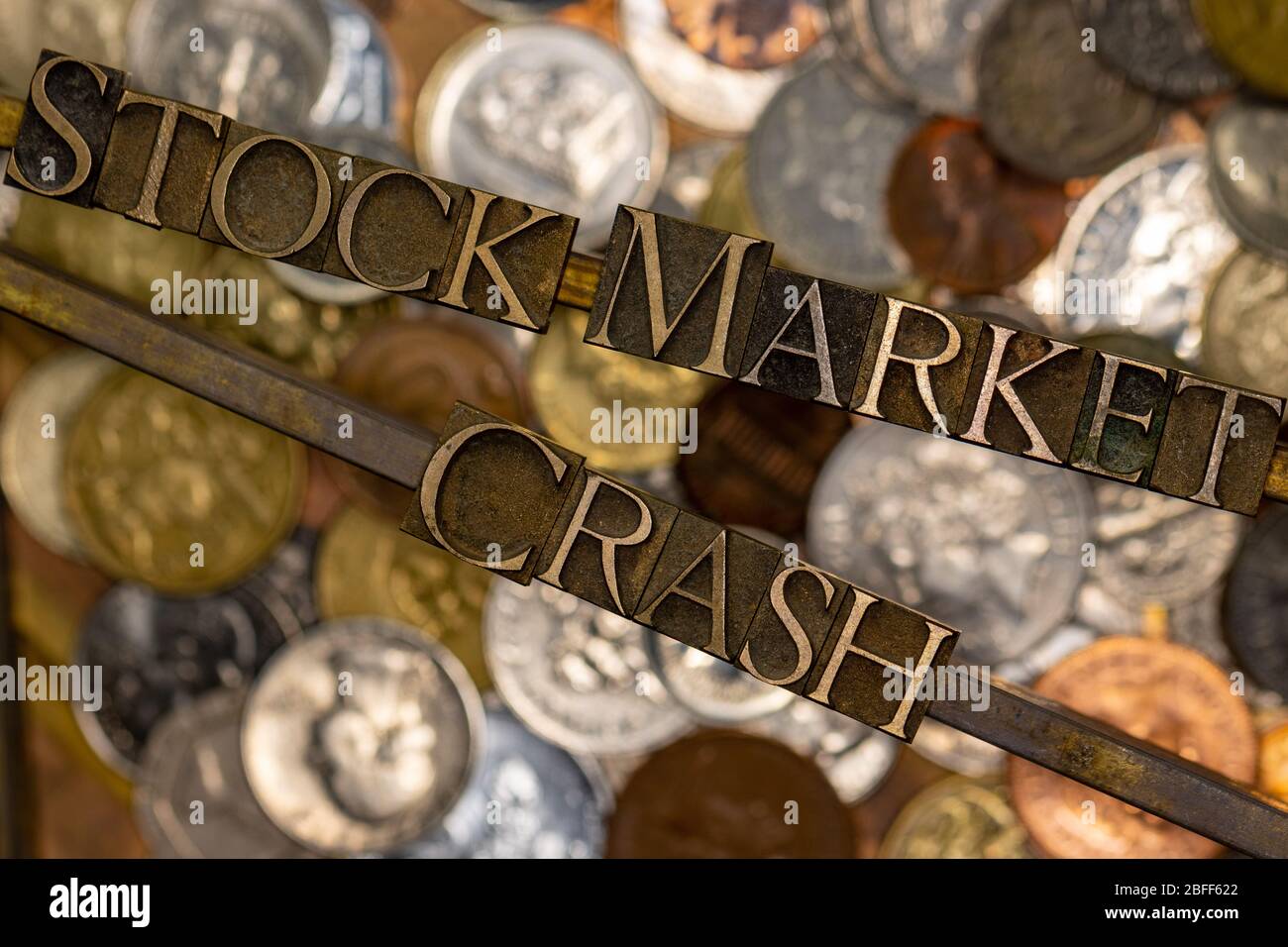 Foto di autentiche lettere typeset che formano il testo di Stock Market Crash posizionato su barre su strato di monete su rame testurizzato vintage grunge Foto Stock