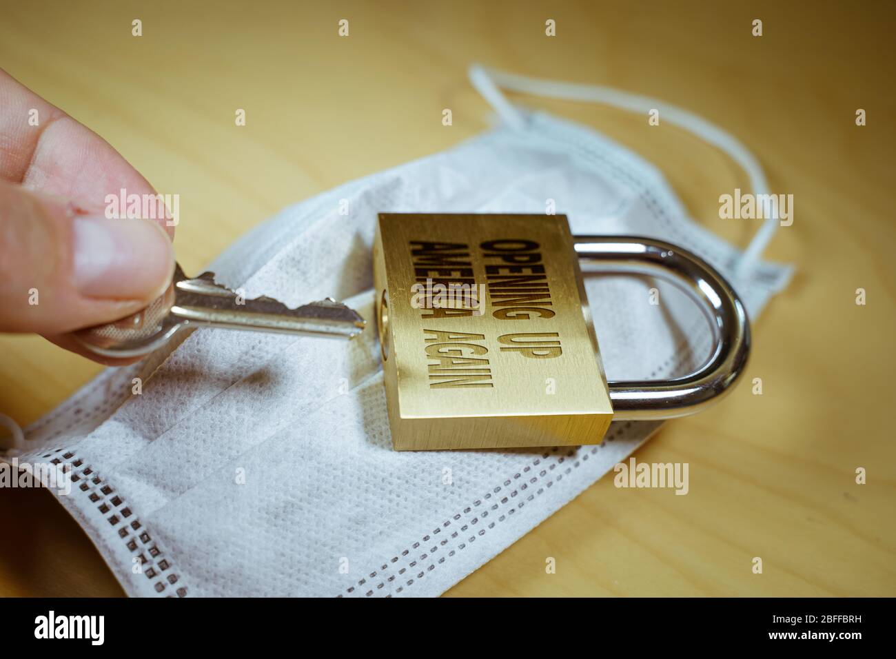 Mano che apre un lucchetto con il testo di apertura in america di nuovo su di esso. Foto Stock