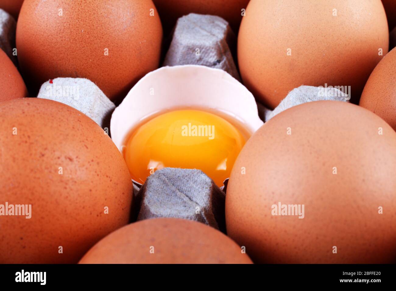 Uova di pollo in un vassoio di carta, un uovo è rotto Foto Stock