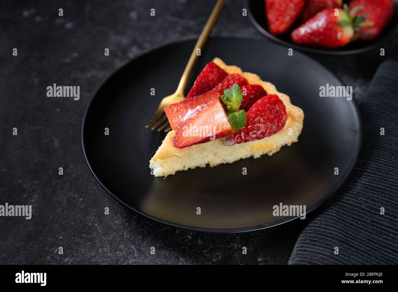 Una pace di torta di fragole su sfondo nero Foto Stock