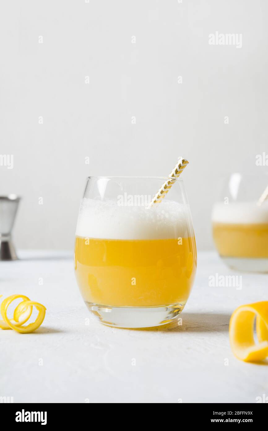 Cocktail di whisky con succo di limone, sciroppo di zucchero e albume d'uovo in vetro su bianco. Orientamento verticale. Primo piano. Foto Stock