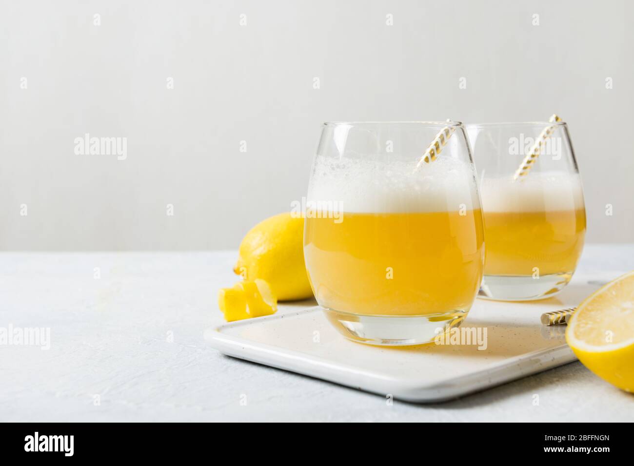 Due cocktail acini con ingredienti, succo di limone, albume in vetro su tavolo bianco. Spazio di copia. Foto Stock